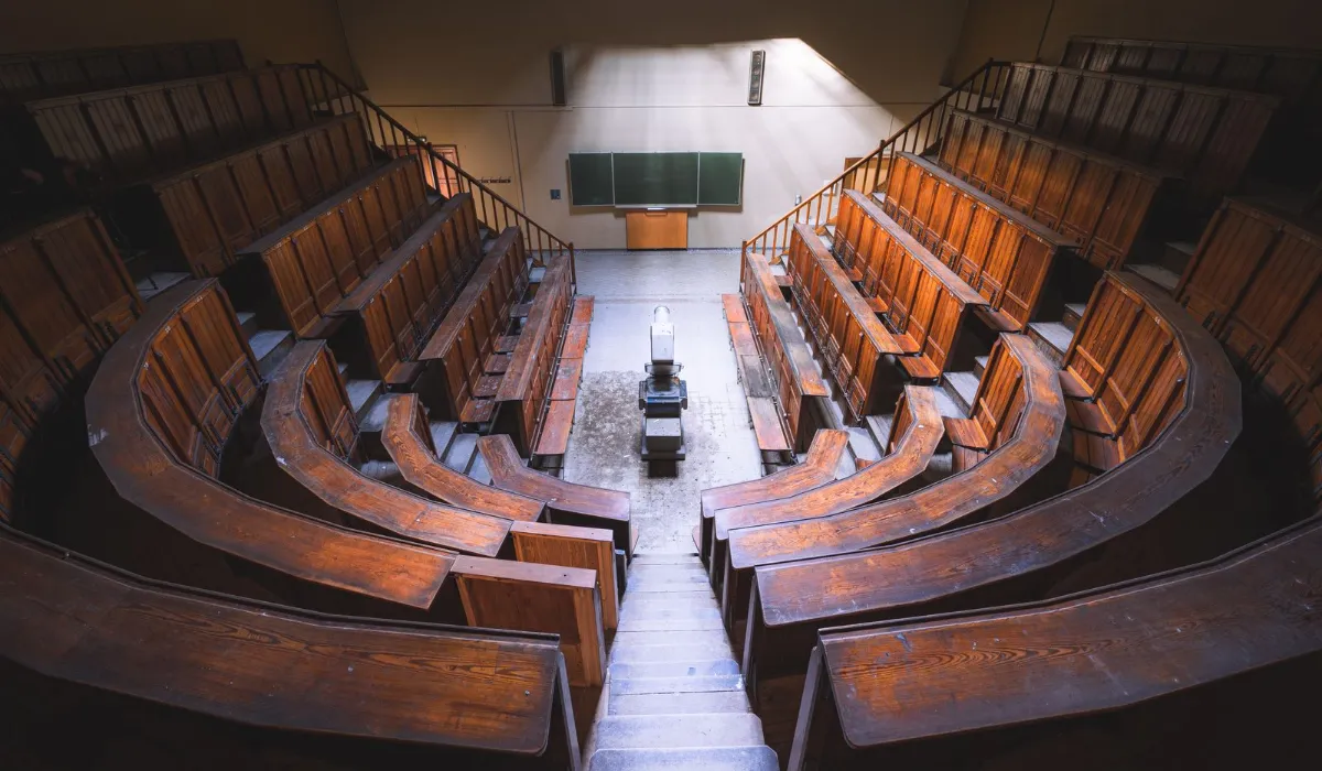 Empty lecture hall with a laptop open on the front desk
