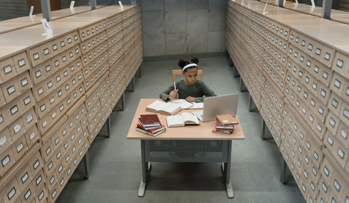 A quiet university library reading room with a student at a laptop