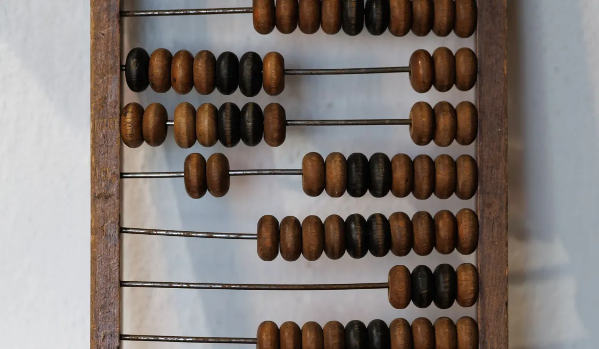 A wooden abacus beside a stack of paper